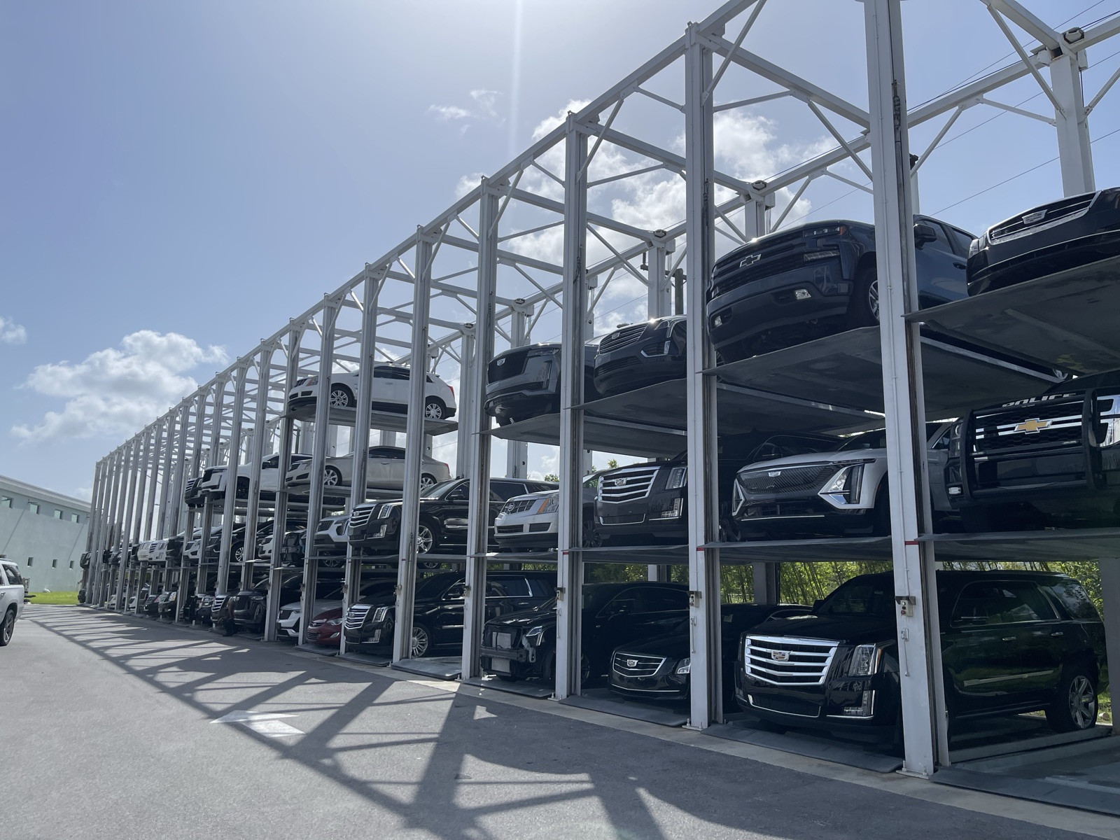 Three levels of SUVs stored on an outdoor stacker structure at a dealership
