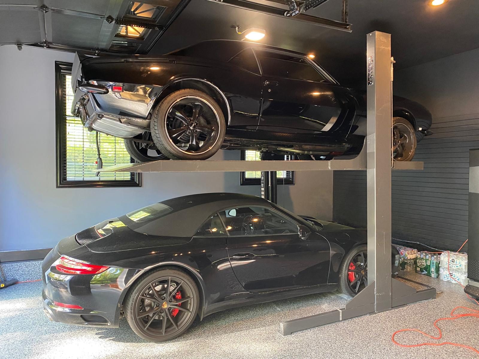 A sports car stored above a convertible in a residential garage