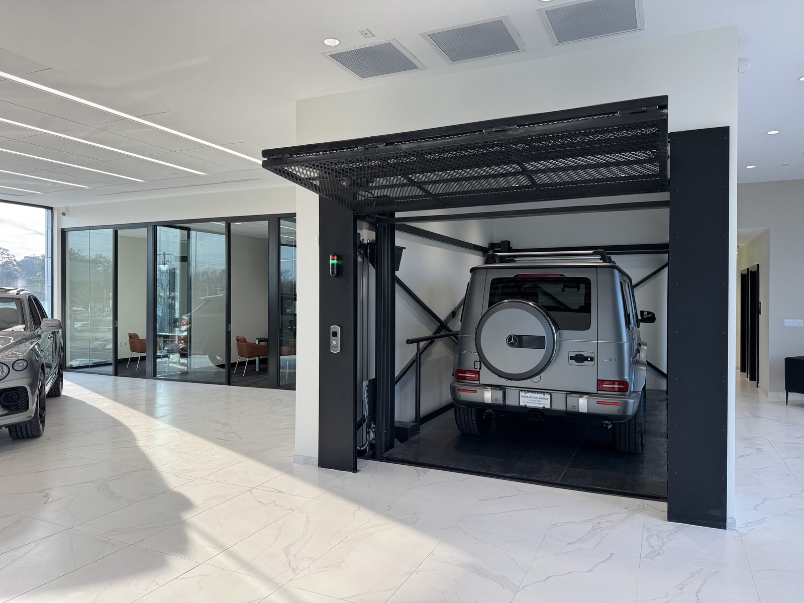A vehicle parked inside the open cabin of a VRC lift in a showroom
